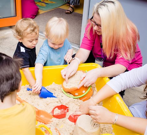 Young children and teachers using a sandpit