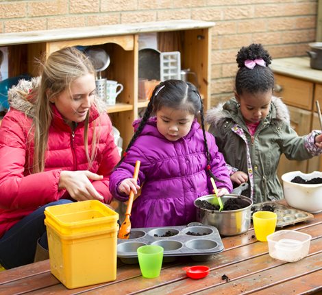Teacher helping young children paint