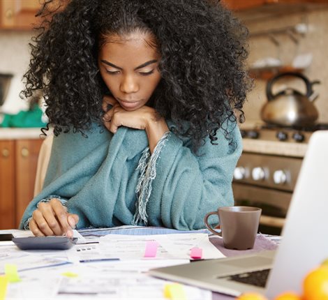 Woman-in-kitchen-looking-at-documents-and-laptop