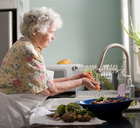 Woman washing a carrot in the sink