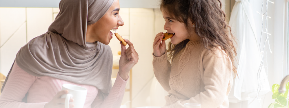 Woman eating cookie with a girl