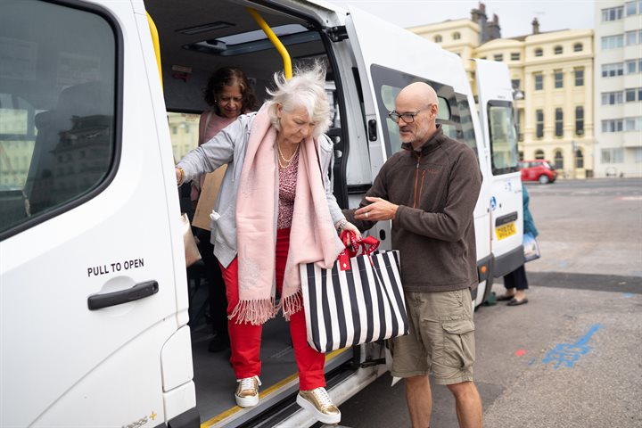 Man helping older woman out of minibus